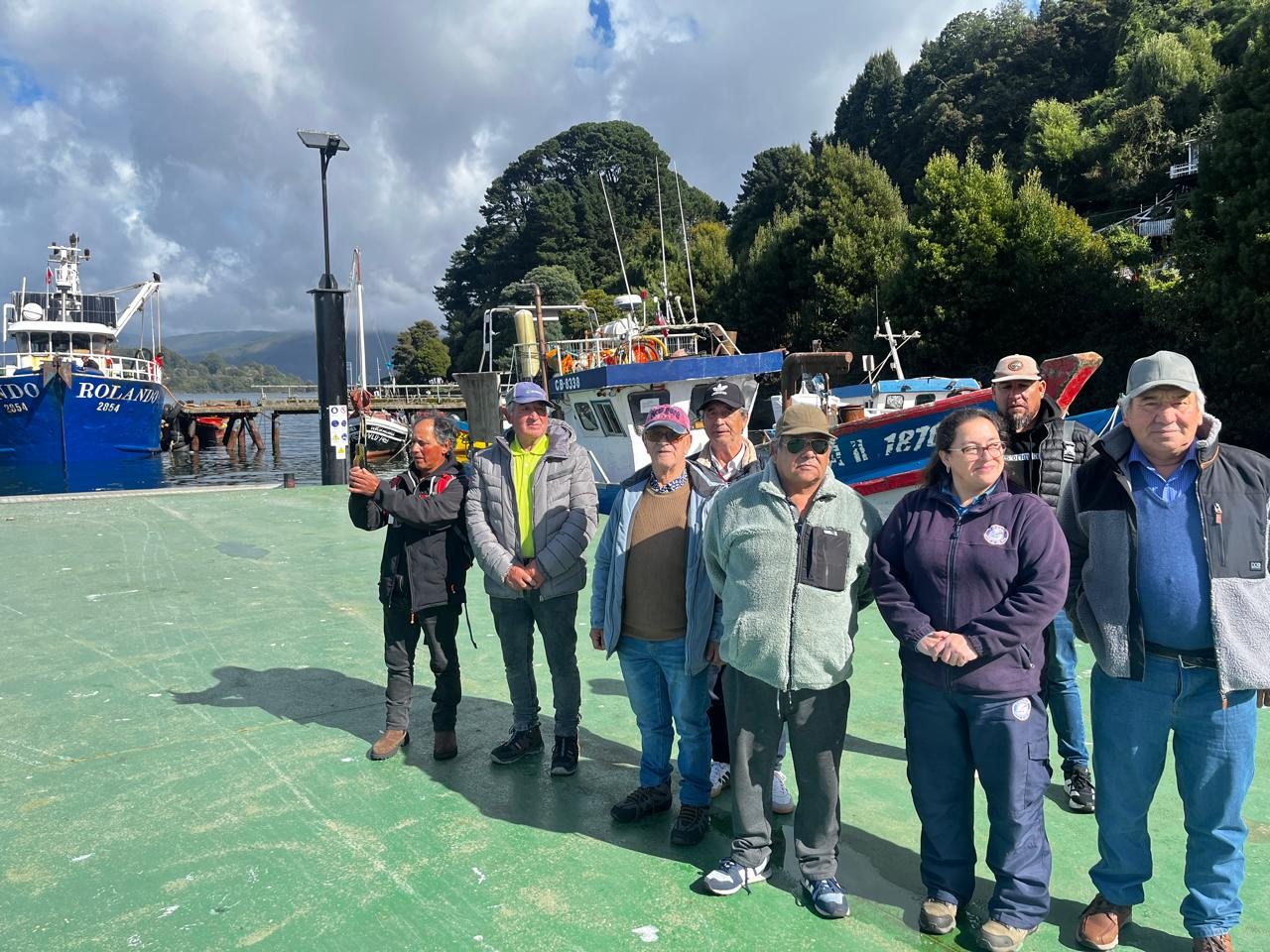 Participantes de la gira tecnológica junto a embarcaciones en una caleta de la comuna de Valdivia.